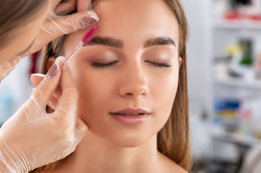 Makyaj sanatçısı kaşların uzun süreli stilini yapar ve kaşlarını boyar. Kaş kaplaması. Profesyonel makyaj ve yüz bakımı..