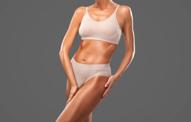 Siyah arka planda bej iç çamaşırlı ince esmer bir kadın. Sağlıklı yaşam tarzı, spor ve diyet.