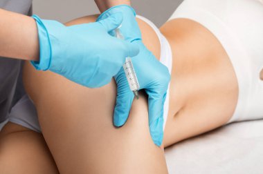 Ozmetolojist bir kadının karnında ve belinde yağ yakmak için lipolitik enjeksiyon yapar. Güzellik salonunda kadın estetiği. Kozmetoloji konsepti..