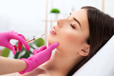 Güzel bir kadının yüzüne dudak büyütme ve kırışıklık önleyici enjeksiyonlar. Güzellik salonunda kadın estetiği..