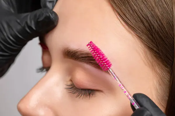 stock image The make-up artist does Long-lasting styling of the eyebrows of the eyebrows and will color the eyebrows. Eyebrow lamination. Professional make-up and face care.