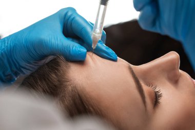 Kozmetik uzmanı, güzel bir kadının burun kıvrımlarında dudak büyütme ve kırışıklık önleyici iğneler yapar. Güzellik salonunda kadın kozmetolojisi.