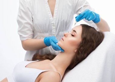 Kozmetik uzmanı güzel bir kadının yüzüne kırışıklık önleyici iğneler yapıyor. Güzellik salonunda kadın estetiği..