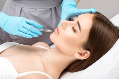 Güzel bir kadının yüzüne dudak büyütme ve kırışıklık önleyici enjeksiyonlar. Güzellik salonunda kadın estetiği..