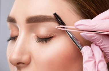 Makyaj sanatçısı kaşların uzun süreli stilini yapar ve kaşlarını boyar. Kaş kaplaması. Profesyonel makyaj ve yüz bakımı..