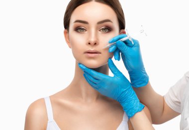 Kozmetik uzmanı, güzel bir kadının burun kıvrımlarında dudak büyütme ve kırışıklık önleyici iğneler yapar. Güzellik salonunda kadın kozmetolojisi.