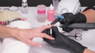 The master of the manicure saws and attaches a nail shape during the procedure of nail extensions in the beauty salon. Professional care for hands.