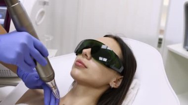 Doktor Güzellik Uzmanı, kuaförde genç esmer bir kadının boynunda lazer dövme temizliği yapıyor. Estetik kozmetoloji, cilt bakımı ve dövme çıkarma.