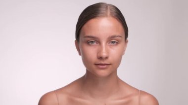 Güzel, mavi gözlü, sağlıklı ciltli genç bir kız gülümseyip kameraya bakıyor..