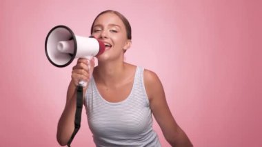 Çizgili tişörtlü güzel, neşeli bir kız izole edilmiş pembe arka planda hoparlöre bağırıyor..