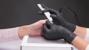Manikür testeresinin ustası güzellik salonundaki tırnak uzatma işlemi sırasında tırnak şekli takıyor. Eller için profesyonel bakım.