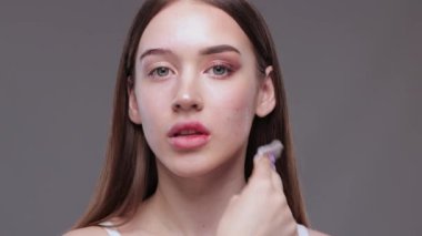Genç ve güzel bir kız makyajını pamukla temizler ve yüzüne ve gözlerine su döker..