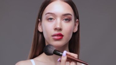 Yüzünün yarısı makyajsız, yarısı makyajsız genç bir kız makyajını yüzünden ve gözlerinden çıkarıyor..