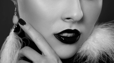 Dudaklarında siyah ruj izi olan bir kadın, Gotik tarzında. Onun beyaz tüylü küpeleri var. Makyaj ve kozmetoloji kavramı.