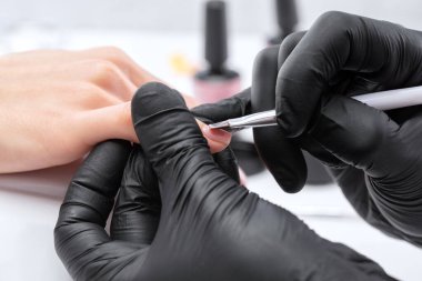 Manikür kürkünün ustası güzellik salonunda jöleyle oje sürüyor. Eller için profesyonel bakım.