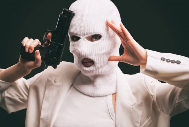 Beyaz kar maskeli bir kadın yüzüne yakın bir silahla karanlık bir arka planda dumanlı..