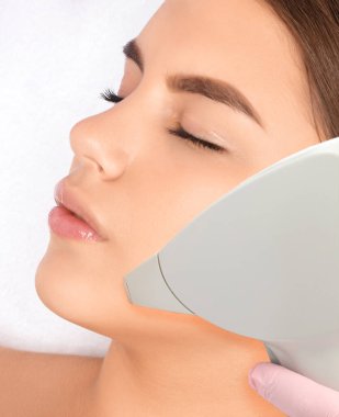Elos epilasyon tüy çıkarma prosedürü bir kadının yüzünde. Güzellik uzmanı bir güzellik salonunda lazer gençleştirme yapıyor. Yüz bakımı. Donanım ipl kozmetolojisi
