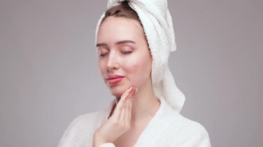 Genç ve güzel bir kız makyajını pamukla temizler ve yüzüne ve gözlerine su döker..