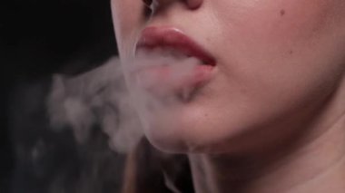 Güzel makyajlı, dolgun dudaklı bir kadın sigarasını yakın plan içer..