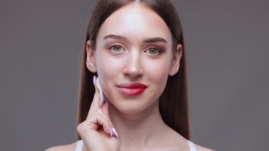 Genç ve güzel bir kız makyajını pamukla temizler ve yüzüne ve gözlerine su döker..