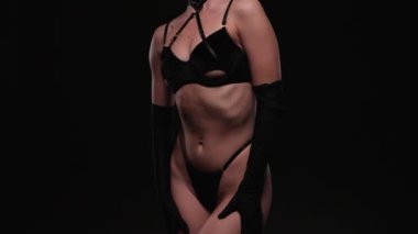 Siyah arka planda siyah seksi iç çamaşırları olan güzel bir kız vücudu. Seksi vücut, kapat.