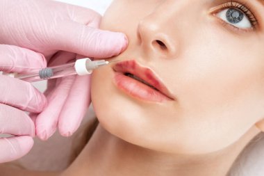 Kozmetik uzmanı güzel bir kadının yüzüne dudak büyütme, kırışıklık önleyici iğneler yapıyor. Güzellik salonunda kadın estetiği..