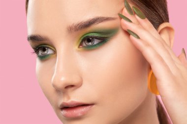 Güzel yeşil makyajlı, temiz tenli, yuvarlak küpeli esmer kız. Makyaj konsepti.