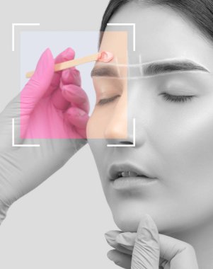 Makyöz, yüz kıllarını aldırma prosedürü uyguluyor. Mavi gözlü güzel bir kız. Kaşlarında daimi makyaj var. Profesyonel makyaj..