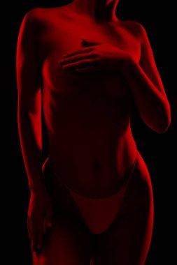 Sıska seksi bir kadın, siyah bir arka planda. Vücudu kırmızı ışıklarla aydınlanıyor..