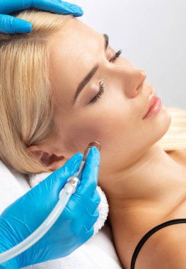 Kozmetik uzmanı, güzellik salonundaki güzel, genç bir kadının yüz derisinin mikro cilt bakımını yapıyor. Kozmetoloji ve profesyonel cilt bakımı..