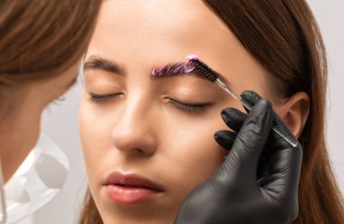 Makyaj sanatçısı uzun süreli kaş stili yapar ve kaşlarını boyar. Kaş kaplaması. Profesyonel makyaj ve yüz bakımı..