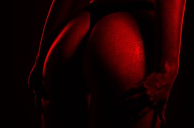 Kırmızı arka planda siyah iç çamaşırlı zayıf seksi kadın. Cildi ıslak, vücudunda su damlaları görünüyor..