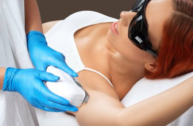 Bir kadının vücudunda epilasyon tüy çıkarma prosedürü. Güzellik uzmanı bir güzellik salonunda lazer gençleştirme yapıyor. İstenmeyen vücut kılları alınıyor. Donanım ipl kozmetolojisi