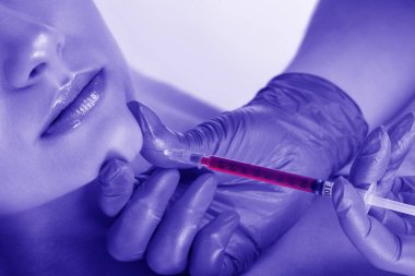 Kozmetik uzmanı, sarı bluzlu güzel bir kadının yüzüne kırışıklık önleyici iğneler yapıyor. Güzellik salonunda kadın estetiği..