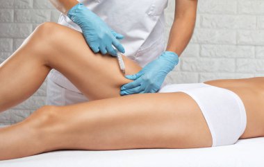 Estetik kozmetik uzmanı bir kadının vücudunda yağ yakmak için lipolitik enjeksiyon yapar. Güzellik salonunda kadın estetiği. Kozmetoloji konsepti..