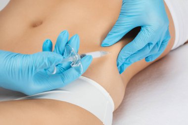 Estetik kozmetik uzmanı bir kadının vücudunda yağ yakmak için lipolitik enjeksiyon yapar. Güzellik salonunda kadın estetiği. Kozmetoloji konsepti..