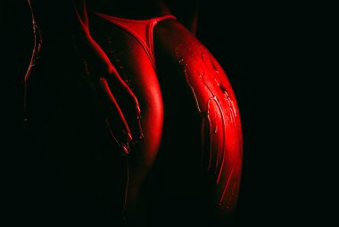 Beautiful sexy ass of young naked woman on black background. Drops of honey flow down on her buttocks