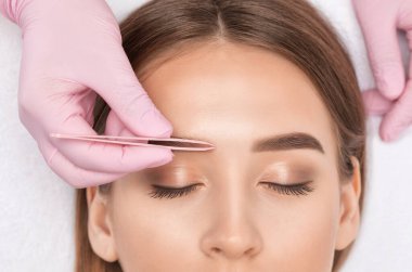 Makyaj sanatçısı uzun süreli kaş stili yapar ve kaşlarını boyar. Kaş kaplaması. Profesyonel makyaj ve yüz bakımı..