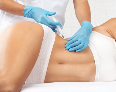 Estetik kozmetik uzmanı bir kadının vücudunda yağ yakmak için lipolitik enjeksiyon yapar. Güzellik salonunda kadın estetiği. Kozmetoloji konsepti..