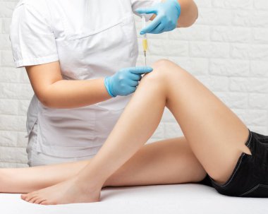 Yaralanmadan sonra bir hastanın dizinde kök hücre tedavisi yapan bir doktor. Diz ağrısını trombosit zengini plazma enjeksiyonuyla tedavi ediyorum. Eklem iltihabı ve osteoartrit tedavisi. Tıbbi ve kozmetik konsepti..