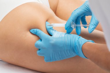 Estetik kozmetik uzmanı bir kadının vücudunda yağ yakmak için lipolitik enjeksiyon yapar. Güzellik salonunda kadın estetiği. Kozmetoloji konsepti..