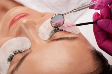 Güzellik salonunda uzun kirpikleri olan güzel bir kadın. Kirpik uzatma prosedürü. Kırbaçlar yakın.