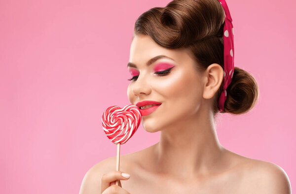 Young beautiful woman with a beautiful hairstyle and bright makeup on a pink background. Professional makeup and facial care.