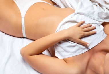 Sabahları beyaz bir yatakta sarışın bir kız. Yatakta çekici bir sporcu figürü olan yetişkin bir kız..