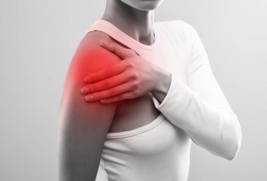 İzole edilmiş beyaz elbiseli ince bir kadın. Kendine omuz masajı yapıyor. Sağlıklı yaşam tarzı, spor ve diyet.