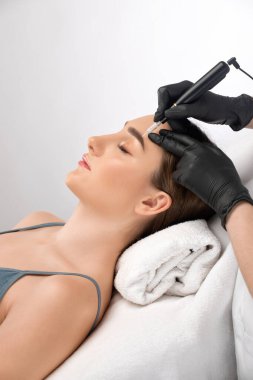 Güzellik salonunda güzel bir kadının kaşları için kalıcı makyaj. Yakından bir güzellik uzmanı kaş dövmesi yapıyor. Gözlerdeki oklar