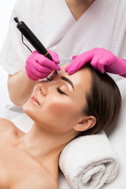 Güzellik salonunda güzel bir kadının kaşları için kalıcı makyaj. Yakından bir güzellik uzmanı kaş dövmesi yapıyor. Gözlerdeki oklar