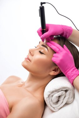 Güzellik salonunda güzel bir kadının kaşları için kalıcı makyaj. Yakından bir güzellik uzmanı kaş dövmesi yapıyor. Gözlerdeki oklar