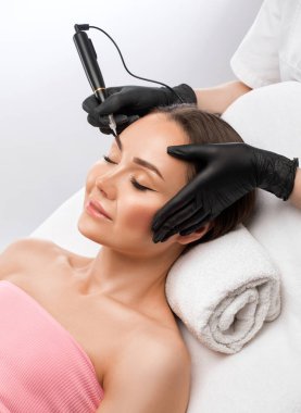 Güzellik salonunda güzel bir kadının kaşları için kalıcı makyaj. Yakından bir güzellik uzmanı kaş dövmesi yapıyor. Gözlerdeki oklar