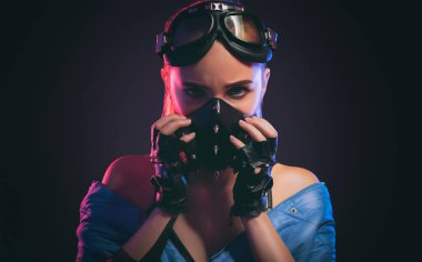 Mavi ceketli bir kızın portresi, siyah koruyucu bir maske, güvenlik gözlüklü siyah eldivenler..